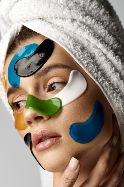 Жінка з рушником на голові і з плямами очей на її обличчі, демонструючи спокійну і трансформаційну рутину краси. - Фото, зображення