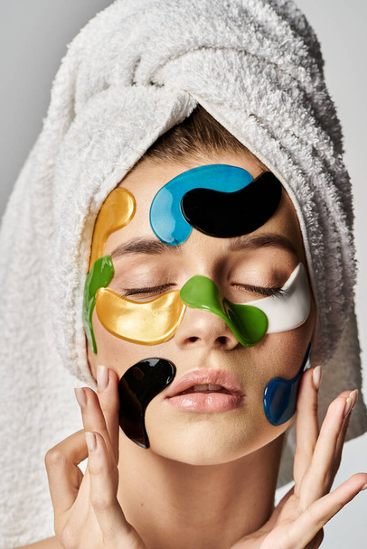 Une jeune femme sereine avec une serviette sur la tête, les yeux fermés, mettant en valeur les patchs oculaires. - Photo, image