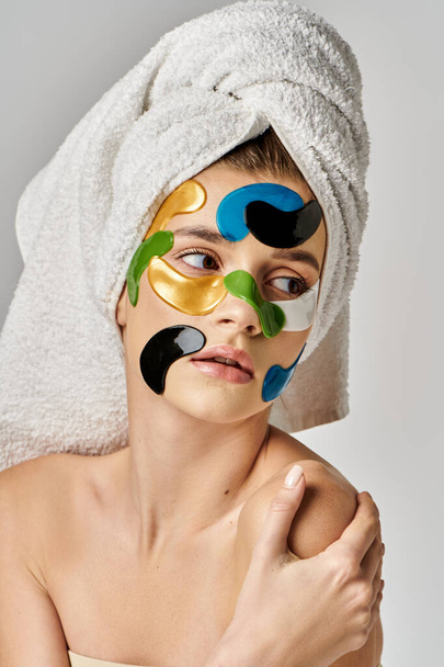 Спокойная молодая женщина с полотенцем, обернутым вокруг головы с повязками на глазах и макияжем. - Фото, изображение