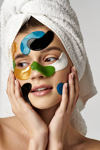 Une jeune femme sereine avec une serviette enroulée autour de sa tête et avec des patchs sur le visage. - Photo, image