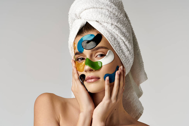 Een serene jonge vrouw omarmt zelfzorg met een handdoek om haar hoofd, presentatie van een schoonheid routine. - Foto, afbeelding