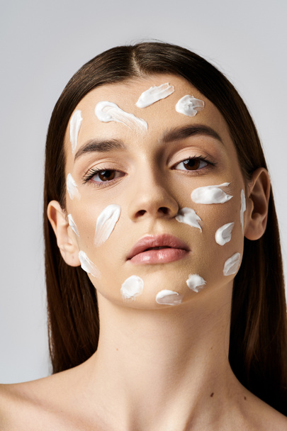 A beautiful young woman with white cream on her face, creating a luxurious and serene image. - Photo, Image