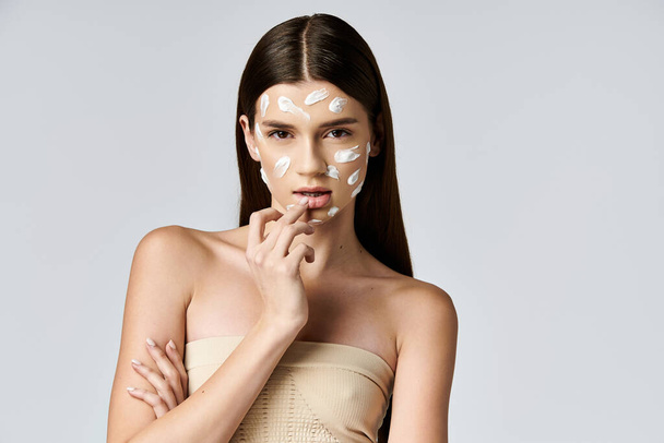 A beautiful young woman posing with white cream on her face, creating a stunning, ethereal look. - Photo, Image