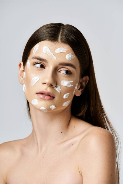 A stunning young woman wearing a white cream on her face, exuding mystery and elegance. - Photo, Image