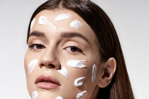 A beautiful young woman posing with an abundance of cream on her face. - Photo, Image