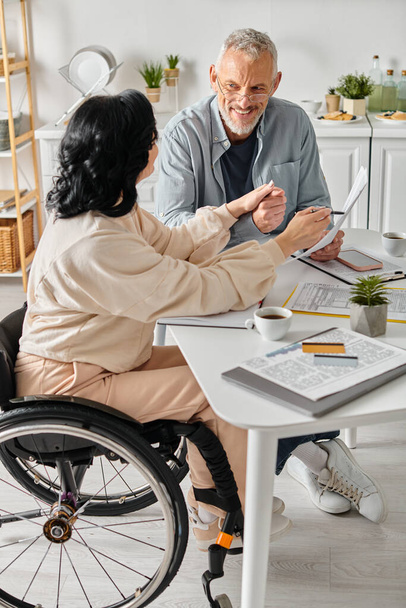 Egy tolószékes fogyatékos nő és gondoskodó férje együtt tervezik a családi költségvetést. - Fotó, kép