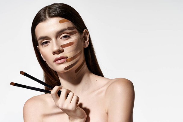 Donna graziosa con vari pennelli per il trucco sul viso, creando un look creativo e artistico con fondazione. - Foto, immagini