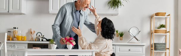happy brunette woman hugging her husband while receiving present from him, banner - Photo, Image