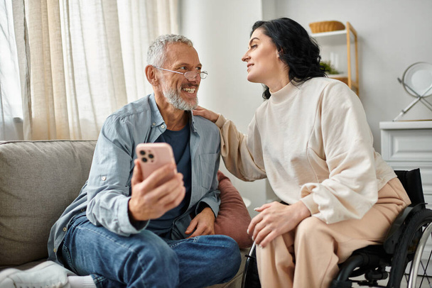 A man in a wheelchair engages in conversation with a disabled woman in a wheelchair in a cozy living room setting. - Photo, Image