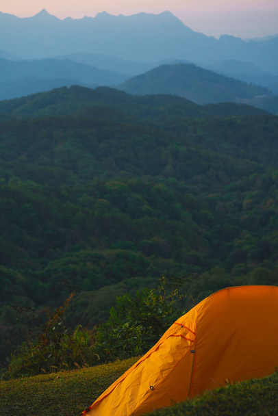 オレンジのキャンプテントと日の出の背景を持つ山の層で旅行する自然 - 写真・画像