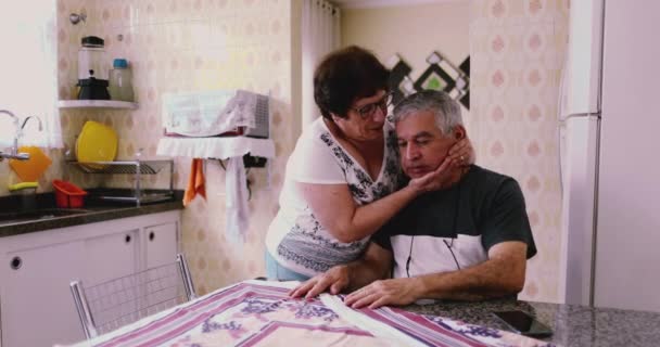 Starší muž čelí životní strádání, pečující manželka poskytuje podporu a pomoc v kuchyni doma - Záběry, video