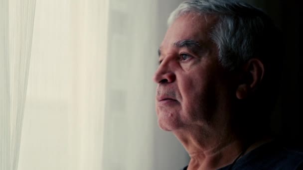 Uomo anziano pensieroso che guarda fuori dalla finestra, profondamente nel pensiero durante la pensione - Filmati, video