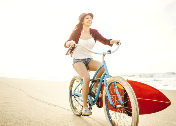 Surfer Woman riding bicycle on beach - Фото, изображение