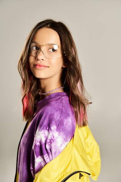 Stylowa nastolatka z pewnością pozuje w żółto-fioletowej kurtce, pokazując jej wyjątkowe poczucie mody i śmiałą osobowość. - Zdjęcie, obraz