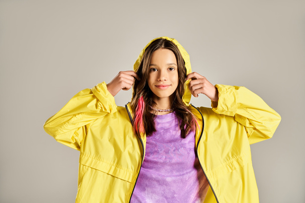 Un adolescent élégant dans un imperméable jaune vif frappant une pose pour l'appareil photo avec énergie et confiance. - Photo, image