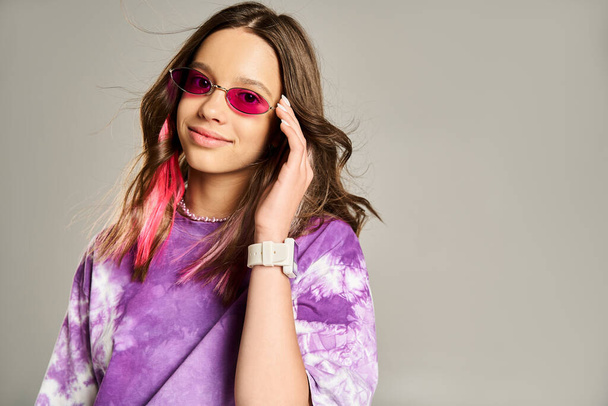 Menina adolescente elegante confiantemente posa no cabelo rosa e camisa roxa, vestindo óculos de sol na moda. - Foto, Imagem