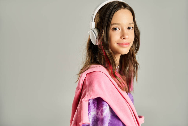 Stylowa nastolatka wygląda spokojnie w żywym szlafroku, aktywnie pozowanie podczas noszenia słuchawek. - Zdjęcie, obraz