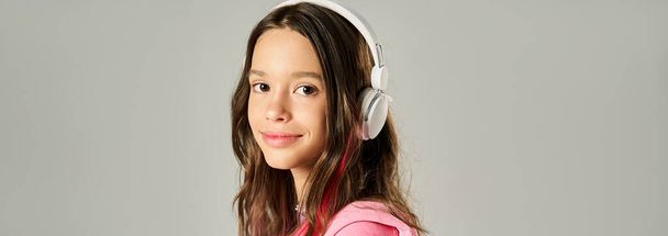Una adolescente con estilo en una vibrante camisa rosa posa con auriculares puestos, exudando un ambiente animado y de moda. - Foto, imagen