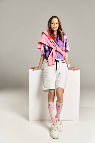 Stilvolles Teenager-Mädchen posiert energisch, trägt ein lila Hemd und weiße Shorts und strahlt Selbstbewusstsein und Lebendigkeit aus. - Foto, Bild