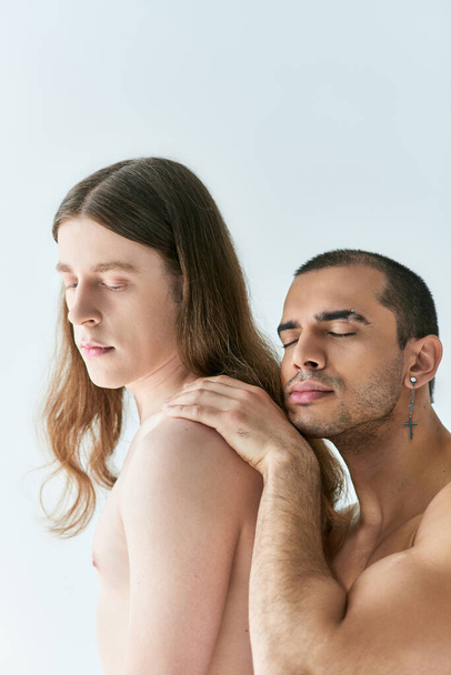 Un hombre sin camisa sosteniendo a otro hombre hombro, transmitiendo afecto. - Foto, imagen
