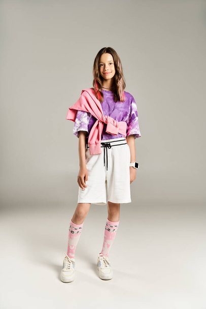 Стильна дівчина-підліток активно позує в яскраво-фіолетовій сорочці і білих шортах, виключаючи елегантність і впевненість. - Фото, зображення