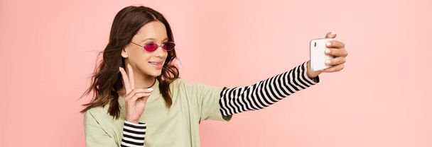 Una ragazza adolescente alla moda in abiti vibranti che si fa un selfie con il suo cellulare. - Foto, immagini