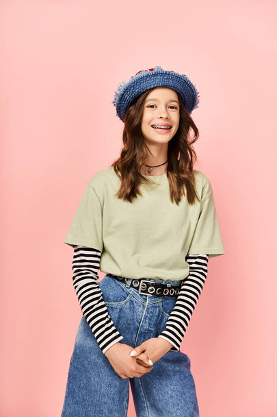 Una adolescente de moda posa enérgicamente en un sombrero azul y jeans. - Foto, imagen