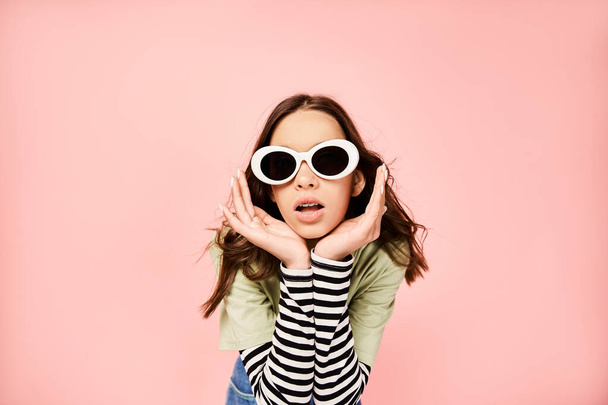 Ein modisches Teenager-Mädchen posiert selbstbewusst in leuchtend grünem Hemd und trendiger Sonnenbrille. - Foto, Bild