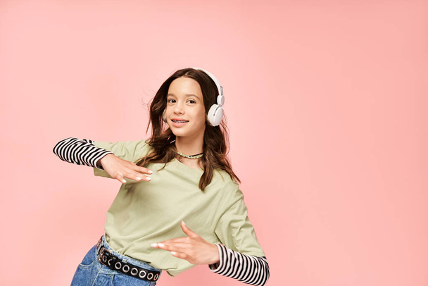 Stylová dospívající dívka v zelené košili pozorně poslouchá hudbu přes sluchátka, vyzařující pulzující a podmanivou auru. - Fotografie, Obrázek