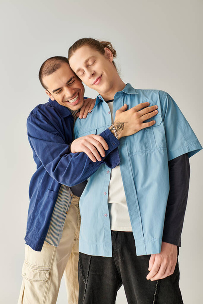 Δύο άντρες αγκαλιασμένοι τρυφερά ενώ στέκονται δίπλα-δίπλα. - Φωτογραφία, εικόνα