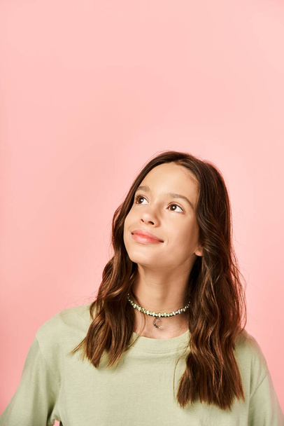 Uma menina adolescente na moda faz uma pose na frente de uma parede rosa brilhantemente colorida com confiança e estilo. - Foto, Imagem
