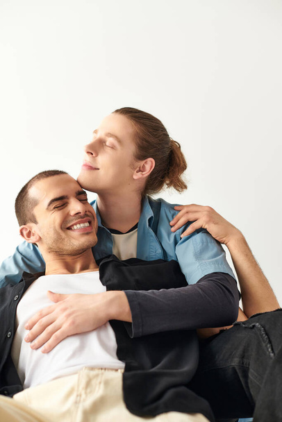 Dos hombres sentados entrelazados uno encima del otro en un abrazo amoroso. - Foto, Imagen