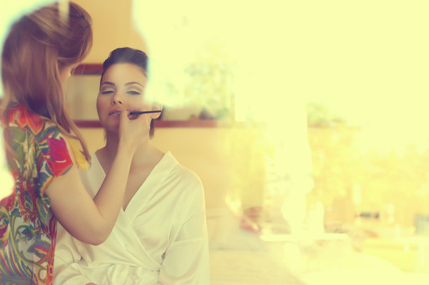 Make-up artist applying make-up on a bride's face - Foto, afbeelding