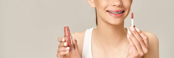 Une adolescente élégante tenant du rouge à lèvres dans une tenue vibrante, mettant en valeur sa personnalité ludique et active. - Photo, image
