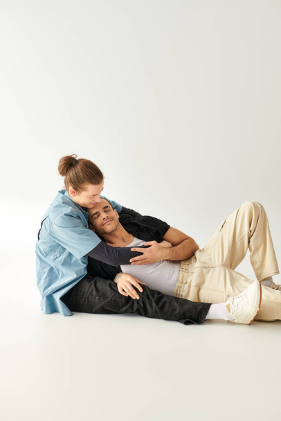 Dos hombres enamorados sentados en el suelo en un entorno sereno. - Foto, Imagen