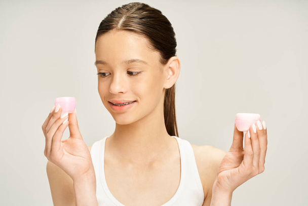 A stylish teenage girl energetically holds cream in her hands. - Photo, Image