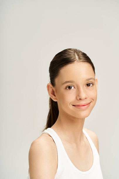 A stylish young girl in a white tank top dances energetically, exuding vibrant charm and lively energy. - Photo, Image