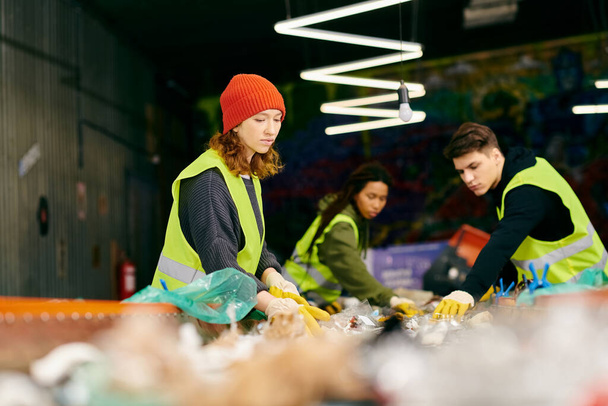 A group of young volunteers in gloves and safety vests stand around a table filled with an abundance of fresh, healthy food. - 写真・画像