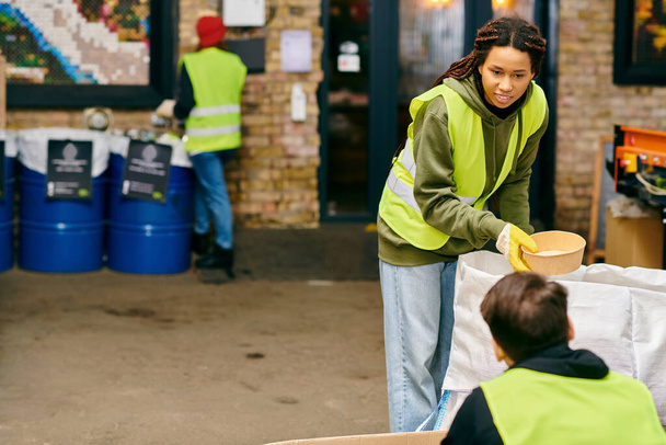 A woman wearing a vibrant yellow jacket, participating in recycling by holding a bowl. - Foto, Imagem