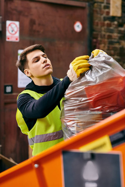 A man wearing a yellow vest holding a bag of waste - Φωτογραφία, εικόνα