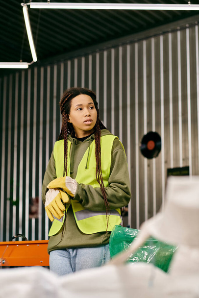 A young volunteer, eco-conscious in gloves and a yellow safety vest, while sorting waste. - Photo, image