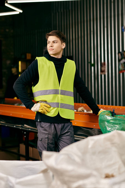 A young volunteer in gloves and safety vest sorting waste in a warehouse. - Foto, Imagen