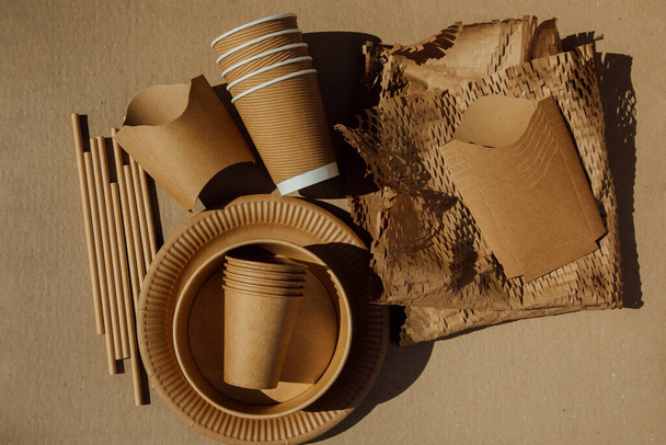 Una serie di utensili di carta e posate di legno su uno sfondo marrone. Eco-friendly, zero rifiuti concetto. Vista dall'alto - Foto, immagini