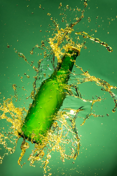 Green beer bottle with splashing liquid - Foto, Imagen