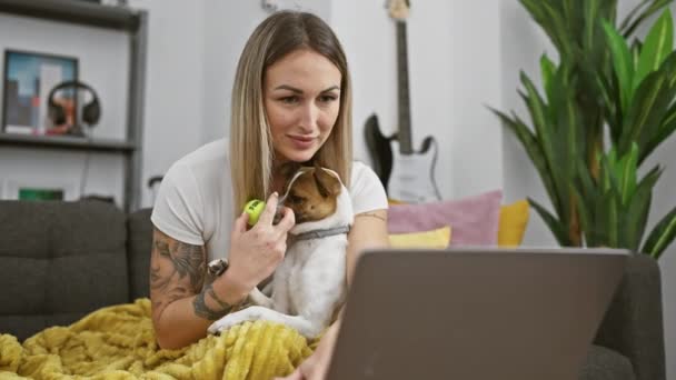 Nainen nauttii aikaa kotona koiransa kanssa työskennellessään kannettavan tietokoneen parissa, mikä herättää etätyön, lemmikkieläinten ja elämäntavan teemoja.. - Materiaali, video
