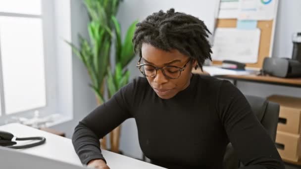 A focused african american woman with dreadlocks wearing glasses at an office setting. - Footage, Video