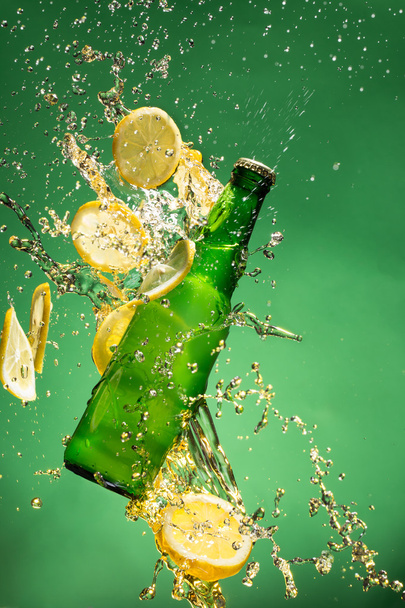 Green beer bottle with splashing liquid - Foto, Imagen