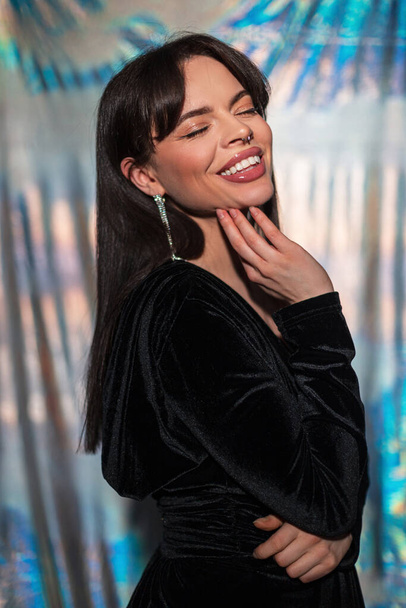 Kaunis muodikas nuori onnellinen tyylikäs nainen, jolla on makea hymy illalla muoti mekko alhainen v pääntie studiossa holografinen tausta - Valokuva, kuva