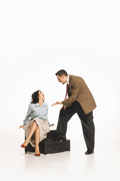 Man in suit gesturing at seated woman on the floor. Couple quarreling, emotionally arguing. Young elegant woman expressing disagreement. Concept of retro and vintage, relationship, human emotions - Foto, Imagem