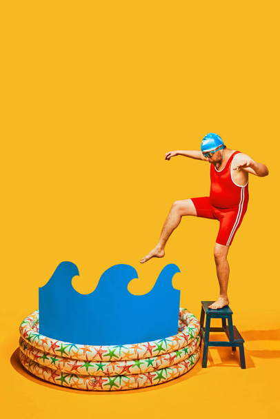 Komik adam, sarı stüdyo arka planında çocuk havuzuna dalmadan önce tabureye çıkıp su denemeye kalkıyor. Pop sanatı, spor, eğitim, rekabet, hobi, aktivite kavramı. - Fotoğraf, Görsel